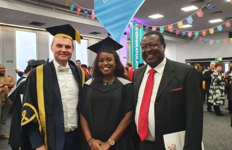 ANC party leader Musalia Mudavadi (right) poses for a photo with his daughter, Maryanne Mudavadi (center) during a graduation ceremony at the University of Sussex.