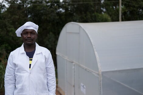 Charles Wachira pauses outside the groups' greenhouse.