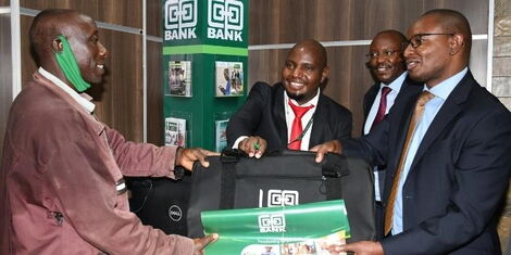 Director Retail & Business Banking William Ndumia presents a gift to Mr Joseph Kimathi Ndegwa, the first client who opened an account after the official opening of the Co-op Kamulu branch. Looking on is the bank's Head of Branch Banking Peter Kirugu.