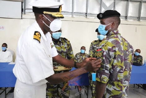 Deputy Commander Kenya Navy and also the Commander Kenya Navy Fleet Brigadier Lawrence Gituma bestows one of the graduates with a Marine Commando badge.