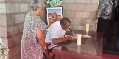 Former First Lady Margaret Kenyatta (left) watches as retired President Uhuru Kenyatta (right) signs the late George Magoha's condolence book on Tuesday, January 31, 2023