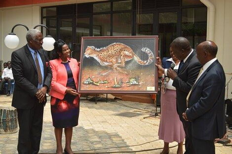 Former KU VC Olive Mugenda (in salmon coloured blazer) presenting a painting to former Interior CS Fred Matiang'i (holding microphone)