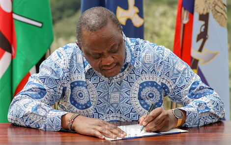 Former President Uhuru Kenyatta signing bill into law during a past event at State House, Nairobi