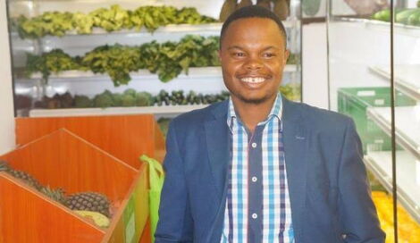 Goldenscape CEO Peter Wangai stands next to some of the produce from his greenhouses.