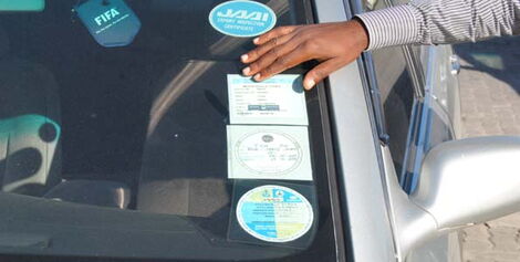 File photo of a motorist checking insurance sticker on his car