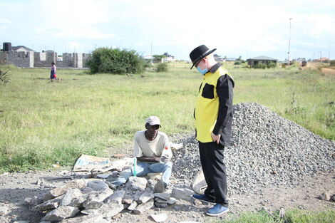 Nominated MP Isaac Mwaura (standing) with David Kang'ee at his work station in Ruiru on Wednesday May 7.