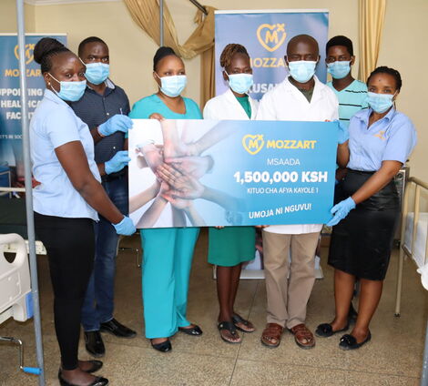Kayole 1 Health Centre Staff and Mozzart team pose for a photo with the dummy cheque representing the sum of the donation.