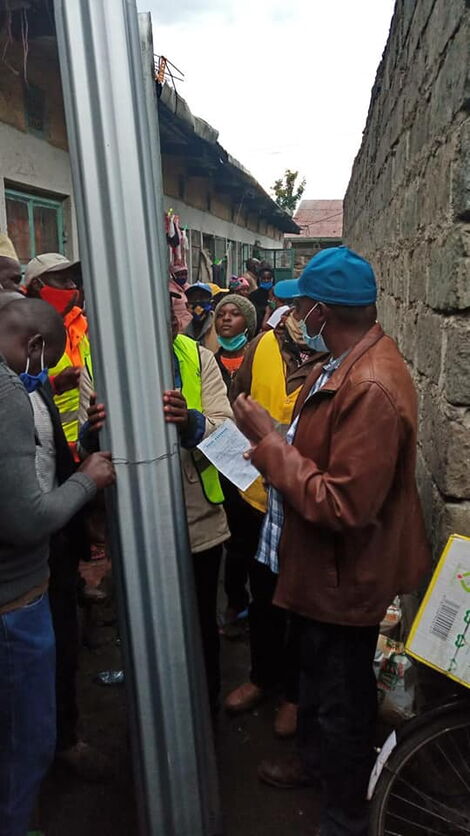 Kimani Ngunjiri hands the new roofing sheets to the family on May 5, 2020.