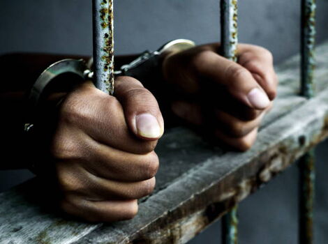 A man in handcuffs behind bars
