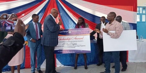 Image of Milly Nafula receiving scholarship from Mount Kenya University founder Prof Simon Gicharu.