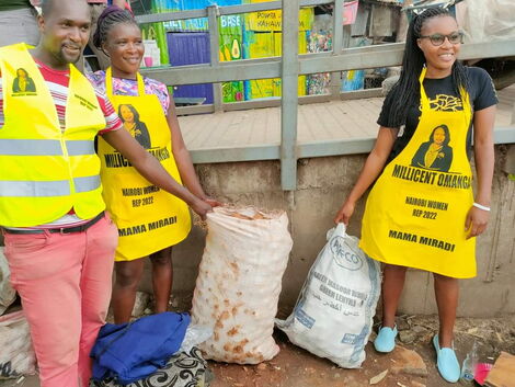 Nominated Senator Millicent Omanga takes a photo with Bevalyn Kwamboka with sacks of potatoes and the branded aprons on Tuesday, October 5.