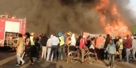 On looker watch as the fire that broke out at Hamza Estate along Jogoo Road on Friday, February 11
