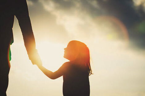 A silhouette of a little girl holding a hand. 