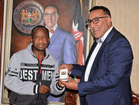 Patrick Kilonzo Mwalua receiving the Head of State Commendation (HSC) Award to from Tourism CS Najib Balala for his invaluable service of supplying drinking water to wild animals at the Tsavo National Park.