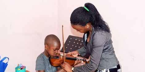 A music teacher showing their student how to play a violin 