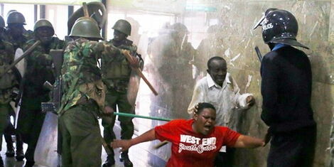 Police assault a Kenyans on March 27, 2020, as the nationwide curfew commenced