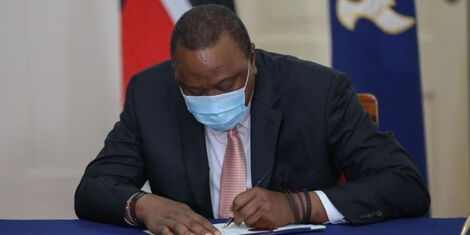 President Uhuru Kenyatta sign a document at State House.