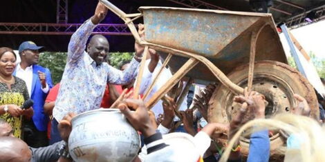 President William Ruto holds a wheelbarrow during his campaign period