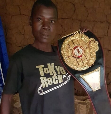 Legendary boxer Conjestina Achieng poses with one of her titles at her home in Siaya County