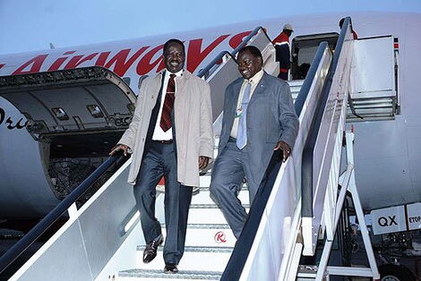 ODM leader Raila Odinga (left) disembarks from a plane at JKIA