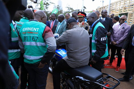 President William Ruto (center) tries a new motorcycle during an interaction with traders at the official launch of the Hustlers' Fund held on November 30, 2022. 