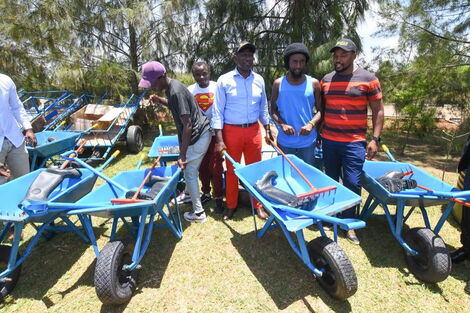 Deputy President William Ruto (center) presents wheelbarrows to youths at a past event.