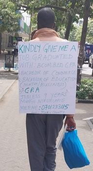 Samuel Meeme with a placard on his back begging for a job.