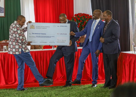 President Uhuru Kenyatta (left) and CBK Governor Patrick Njoroge touch legs as he hands over the Ksh7.4 billion check at State House, Nairobi on March 20, 2020.