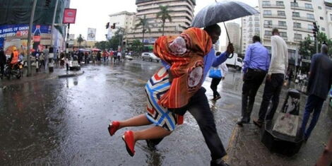 A man helps a woman cross flooded street in Nairobi