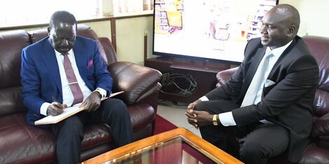 ODM Leader Raila Odinga (left) sugns the visitor's book at the office of the department of immigration in Nyayo House, Nairobi,. Looking on is Citizen Services PS Julius Bitok. 