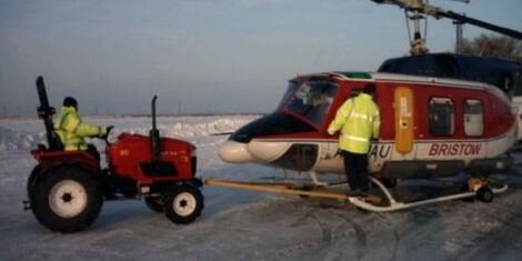A photo of a tractor pulling a helicopter on a handling wheels. 