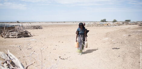 An archive image of a woman carrying jerry cans of water in Kenya.