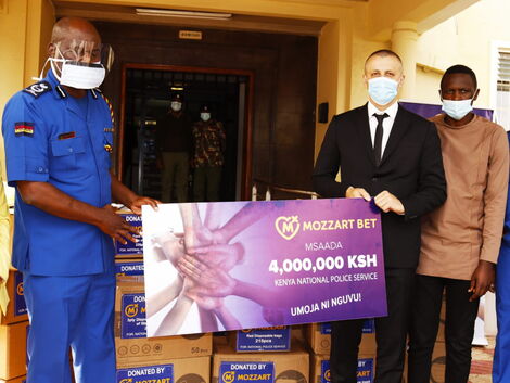 Nyale Munga, the Principal Assistant to the Inspector General of Police Hilary Mutyambai and Mozzart Country Manager Sasa Krneta hold a dummy cheque during the donation of Ksh 4 million Covid-19 safety equipment.