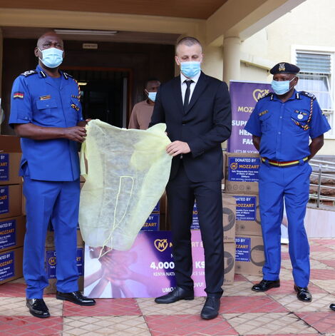 Nyale Munga, the Principal Assistant to the Inspector General of Police Hilary Mutyambai and Mozzart Country Manager Sasa Krneta hold a dummy cheque during the donation of Ksh 4 million Covid-19 safety equipment.