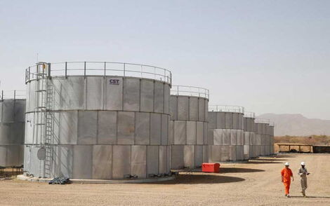 Workers walk past storage tanks at Tullow Oil's Ngamia 8 drilling site in Lokichar, Turkana County.