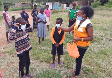 A volunteer hands over masks to children in Kajiado County in May 2020