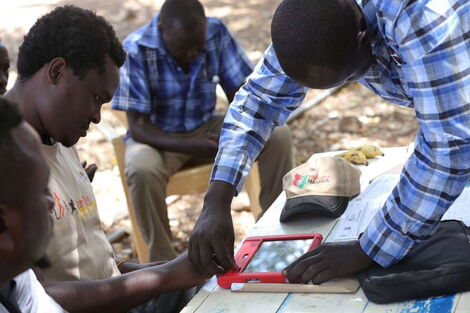 A photo of a Huduma Namba agent collecting biometric data of a citizen.
