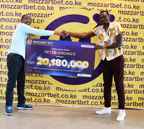 Image of Peter Kirunge receiving his cash prize from Mozzart Bet.