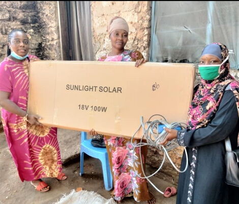  Diana Chitsaka Mwangala, a team leader and founder of Gift A Girl Child Initiative, presents a solar light to the mother of Salim Khamisi.