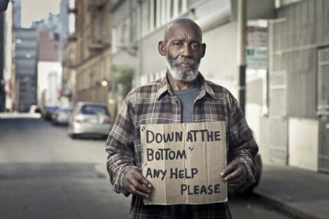 A man holding up a sign asking strangers for help.