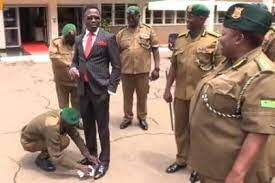Corporal Dickson Loyerer cleaning CS Ababu Namwamba's shoes at NYS headquarters.
