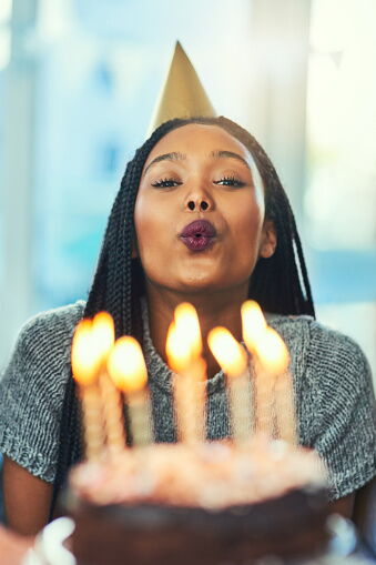 A lady blowing out candles on her birthday cake