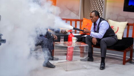 Citizen TV anchor Jeff Koinange using an extinguisher during an interview on JKL in 2019.