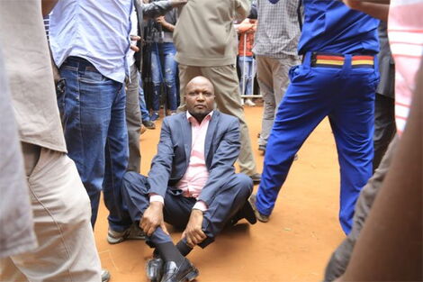 Police officers shielding Gatundu South MP Moses Kuria (seated) from bouncers who wanted to eject him from BBI rally in Kitui on February 1, 2020.