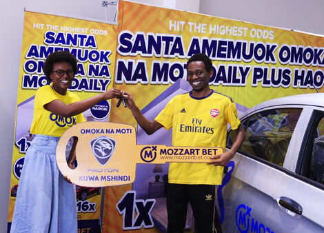 A Mozzart Bet official (left) hands over a car dummy key to University of Nairobi law student Erick Martin Wafula on Friday, December 31