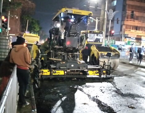 Road contractors recarpeting Moi Avenue at night 