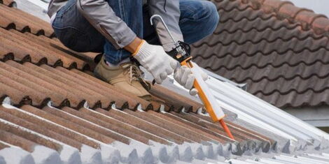 A man applying a sealant to a roof.