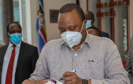 President Uhuru Kenyatta signing a ball after meeting with leaders from Western Kenya on July 1, 2020.