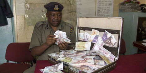 A police officer displays fake money recovered in an operation
