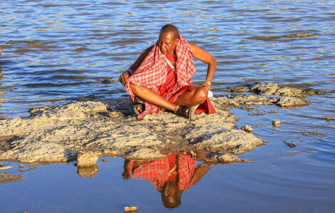 A file photo of a man seated on a rock in the middle of a water source in Olergasile village.